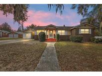 Charming single-story brick home with a walkway leading to a welcoming red porch and mature landscaping at 448 E Waldo St, Groveland, FL 34736