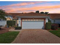 Inviting single Gathering home with a brick driveway leading to an attached two-car garage with a tile roof at 5056 Harbour Dr, Oxford, FL 34484
