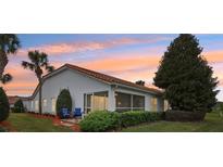 A home's rear exterior shows a screen porch, landscaping, and chairs to sit and enjoy the backyard at 5056 Harbour Dr, Oxford, FL 34484