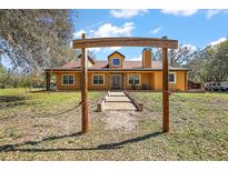 Charming home featuring a rustic wooden archway, lush landscaping, and a welcoming entrance at 6813 S Fork Ranch Dr, Clermont, FL 34714