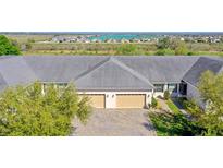 Charming villa with a brick driveway, three-car garage, and serene water view, perfect for luxurious living at 1017 Green Gate Blvd, Groveland, FL 34736