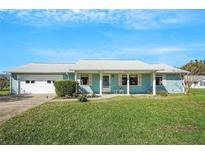 Charming single-story home with a well-maintained lawn and attached garage, painted in a cheerful blue hue at 1033 Scotch Pine Ct, Leesburg, FL 34788