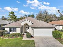 Beautiful single-story home featuring a well-manicured lawn, charming landscaping, and a two-car garage at 11684 Sw 72Nd Cir, Ocala, FL 34476
