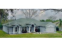 Charming single-story home with blue exterior, white trim, well-manicured lawn, and an attached two-car garage at 11727 Pineloch Loop, Clermont, FL 34711