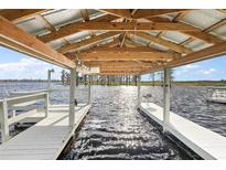 Covered boat dock featuring a white wooden pier and exposed beams, overlooking the sparkling water at 1401 W Highway 50 # 173, Clermont, FL 34711