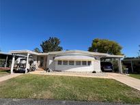 Charming single-story home with dual carports, manicured lawn, and light brick skirting at 146 Jacaranda Dr, Leesburg, FL 34748