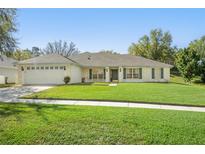 Charming single-story home boasts a well-manicured lawn, attached garage, and inviting front porch, perfect for curb appeal at 1792 Presidio Dr, Clermont, FL 34711