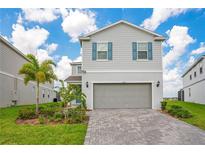 Charming two-story home with light gray siding, blue shutters, and a meticulously paved driveway at 2116 Lelani Cir, Davenport, FL 33897