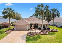 Beautiful tan home with well manicured lawn, decorative fountain, and mature palm trees at 2126 Sansores St, The Villages, FL 32159
