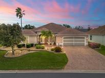 Charming single-story home boasting lush landscaping and a brick driveway, with a two-car garage at 2410 Tamarindo Dr, The Villages, FL 32162
