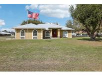 Charming single-story home featuring a well-manicured lawn, a red door, and an American flag on a sunny day at 3909 Cr 532A, Bushnell, FL 33513