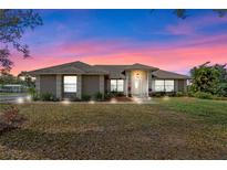 Beautiful single-story home with a well-maintained lawn and mature landscaping, set against a vibrant twilight sky at 7729 Lake Andrea Cir, Mount Dora, FL 32757