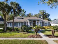 Charming single-story home featuring a landscaped front yard, complemented by palm trees and lush greenery at 114 Cherry Creek Cir, Winter Springs, FL 32708