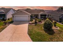 Beautiful home featuring a two-car garage, manicured lawn, and lovely landscaping for great curb appeal at 16721 Se 77Th Northridge Ct, The Villages, FL 32162