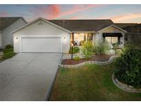 Charming single-story home featuring a well-manicured front yard, attached two-car garage and covered front porch with seating at 16721 Se 77Th Northridge Ct, The Villages, FL 32162