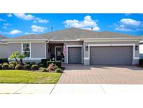 Charming single-story home boasts a manicured lawn and a brick-paved driveway leading to a two-car garage at 203 Silver Maple Rd, Groveland, FL 34736