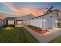 Charming single-story home featuring a well-manicured lawn and a cozy front porch at sunset at 2189 Broxton Pl, The Villages, FL 32162