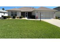 Well-maintained single-story home featuring a lush green lawn and manicured shrubbery at 3183 Hatch Ln, The Villages, FL 32162