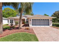 Charming single-story home with well-manicured landscaping, brick driveway and mature palm trees in a lush, green setting at 32800 Oak Park Dr, Leesburg, FL 34748