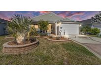 Charming home featuring manicured lawn, decorative landscaping, and a two-car garage with an upgraded driveway at 3786 Stephanie Way, The Villages, FL 32163