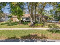 Charming single story home featuring manicured lawn and mature trees, with stone accents around the exterior at 4208 Winderlakes Dr, Orlando, FL 32835