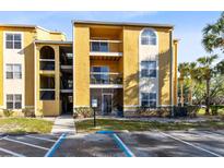 Condo with a yellow exterior, balconies, and well-maintained landscaping at 5255 Images Cir # 207, Kissimmee, FL 34746