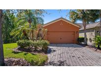 Charming single-story home features lush landscaping, a brick driveway, and a neutral-toned two car garage at 906 Shady Canyon Way, Poinciana, FL 34759