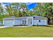 Charming single-story home featuring a two-car garage, neutral paint, and a well-manicured front yard at 12444 Sw 76Th Ln, Dunnellon, FL 34432