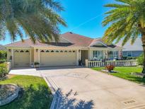 Charming home featuring a three-car garage, beautifully landscaped yard, and inviting front porch at 1430 Hillstream St, The Villages, FL 32163