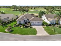 Beautiful single-story home featuring a well-manicured lawn, lush landscaping, and a three-car garage near the golf course at 1726 Augustine Dr, Lady Lake, FL 32159