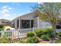 View of the rear of a home featuring a white picket fence, small shrubs, and a screened lanai at 2602 Young Ln, The Villages, FL 32163