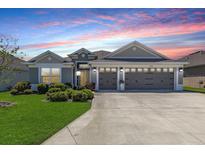 Charming single-story home featuring a well-manicured lawn, a spacious driveway, and a convenient three-car garage at 3334 Pierluissi Path, The Villages, FL 32163