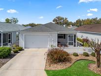 Charming single-story home featuring a well-manicured lawn, white picket fence, and attached two-car garage at 3382 Carrabelle Ct, The Villages, FL 32163