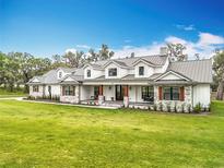 Stunning two-story farmhouse with a metal roof, stone accents, dormer windows, and a welcoming front porch at 464 Long & Winding Rd, Groveland, FL 34736