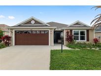 Charming single-story home featuring a well-manicured lawn and attached two-car garage at 5510 Thome Loop, The Villages, FL 32163