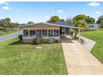 Well-maintained home with manicured lawn and front screened-in porch with long driveway in a quiet community at 802 Weeping Willow Ave, The Villages, FL 32159