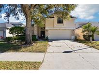 Two-story home with a large tree in the front yard and a two car garage at 8051 Saint James Way, Mount Dora, FL 32757