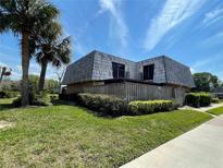 Inviting two-story townhome with a unique roofline, well-maintained lawn, and tropical landscaping at 1000 Royal Oak Blvd, Leesburg, FL 34748