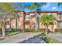 Charming two-story townhome featuring lush landscaping, brick-paved driveway, and lovely curb appeal at 1144 Calabria Ave, Davenport, FL 33897