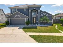 Attractive two-story home with a well-manicured lawn, neutral paint, and a two-car garage at 13519 Bristlecone Cir, Orlando, FL 32828