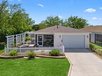 Charming home with a white picket fence, a fountain, and a screened patio, offering a cozy and inviting curb appeal at 2234 Braxton St, The Villages, FL 32162