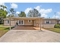 Cozy home featuring a covered carport and a charming entrance with double doors and tidy landscaping at 2350 Conestoga Dr, Leesburg, FL 34748