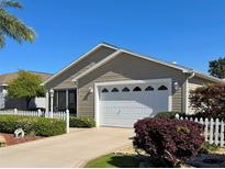 Charming single-story home featuring a well-manicured lawn, tidy landscaping, and an attached two-car garage at 2523 Mariel Way, The Villages, FL 32162