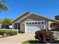 Charming single-story home with a well-maintained lawn and a white picket fence at 2523 Mariel Way, The Villages, FL 32162