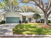 Charming single-story home with a well-maintained lawn, teal garage door, and inviting curb appeal at 25239 River Crest Dr, Leesburg, FL 34748