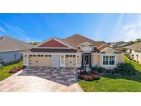 Charming home featuring a three-car garage, landscaped front yard, and beautiful color-coordinated stone driveway at 6126 Mulligan Run, The Villages, FL 32163