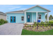 Charming single-story home with light blue siding, a covered front porch, and manicured landscaping at 981 Fiesta Key Cir, Lady Lake, FL 32159