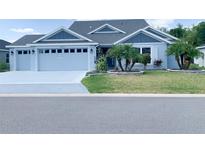 Charming single-story home with blue exterior, manicured lawn, and well-maintained landscaping at 6444 Mcknight Loop, The Villages, FL 34762
