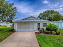 Charming single-story home featuring a well-manicured lawn and a convenient attached garage at 701 Cottage Park Ln, Leesburg, FL 34748
