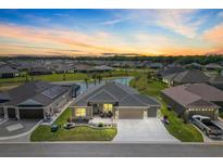 Beautiful single Gathering home featuring lush green lawn, pond view, and attached two car garage at 7250 Trundle Ter, The Villages, FL 34762